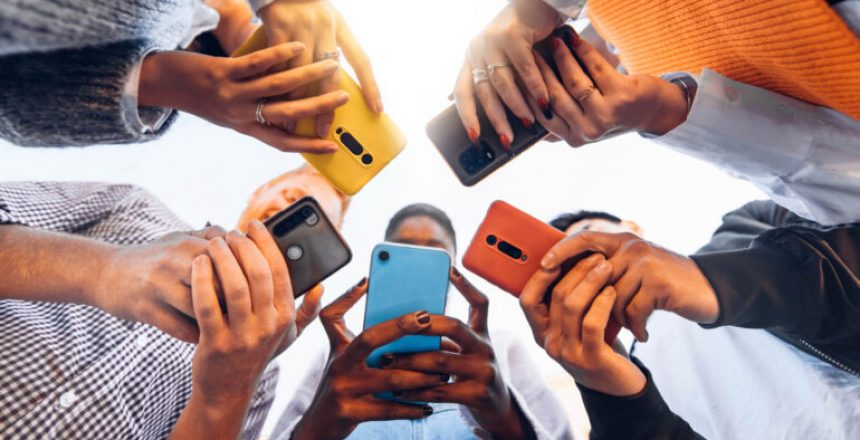 Teens in circle holding smart mobile phones - Multicultural young people using cellphones outside - Teenagers addicted to new technology concept